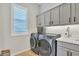 This laundry room features gray cabinets, modern appliances, and ample storage space, enhancing convenience at 2205 E Fallen Leaf Ln, Phoenix, AZ 85024