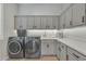 Functional laundry room with gray cabinets, sink, countertop, and modern washer and dryer at 2205 E Fallen Leaf Ln, Phoenix, AZ 85024