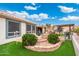 Landscaped backyard featuring lush green grass, a flower bed, and covered patio at 23219 N 145Th Dr, Sun City West, AZ 85375