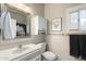 Bright bathroom featuring a sink vanity, mirror, toilet, cabinet, and modern fixtures with a window at 23219 N 145Th Dr, Sun City West, AZ 85375