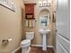 Half-bath with a pedestal sink, toilet, an oval mirror and decorated with earthy tones at 25320 W Heathermoor Dr, Buckeye, AZ 85326