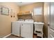 Laundry room featuring a washer, dryer, utility sink, a window, and earthy neutral tones at 25320 W Heathermoor Dr, Buckeye, AZ 85326