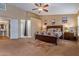 Spacious main bedroom features neutral walls, ceiling fan, wood furniture and attached bathroom at 25320 W Heathermoor Dr, Buckeye, AZ 85326