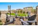 Beautiful backyard features a firepit area, surrounded by Adirondack chairs, green grass and mature landscaping at 25583 S 224Th Pl, Queen Creek, AZ 85142