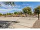 Outdoor basketball court with multiple hoops, benches, and mature trees for recreational activities at 26716 W Ponderosa Ln, Buckeye, AZ 85396