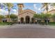 Beautiful clubhouse exterior featuring arched entrances, manicured landscaping, and palm trees at 26716 W Ponderosa Ln, Buckeye, AZ 85396