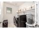 A modern laundry room with front loading washer and dryer and upper storage baskets and a woven hamper at 3603 S Weaver Cir, Gilbert, AZ 85297