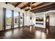 Bright living room with wood floors, beamed ceiling, modern fireplace, and large windows offering desert views at 36430 N 34Th Ave, Phoenix, AZ 85086