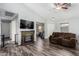 Open-concept living room with dark wood floors, fireplace, ceiling fan, and comfortable brown sofa at 38226 N Kyle St, San Tan Valley, AZ 85140