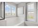 Modern bathroom featuring white tub and shutters on the window for privacy and natural light at 4705 E Betty Elyse Ln, Phoenix, AZ 85032