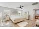 Well-lit bedroom with a ceiling fan, light wood floors, and a bed with a white comforter and decorative pillows at 4705 E Betty Elyse Ln, Phoenix, AZ 85032