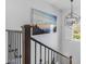 Staircase with metal banisters and dark wood railings, featuring a modern light fixture and landscape wall art at 4705 E Betty Elyse Ln, Phoenix, AZ 85032