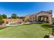 Sprawling backyard with an in-ground pool, putting green, covered patio, and manicured landscaping at 8304 E Inca St, Mesa, AZ 85207