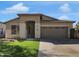 Tan single-story home with a two car garage, arched entry, and manicured lawn, offering curb appeal at 9477 W Tonopah Dr, Peoria, AZ 85382