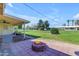 Outdoor patio with fire pit, lush green grass, and mature trees at 10226 W Snead S Cir, Sun City, AZ 85351