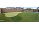 Backyard featuring a custom putting green, swimming pool with waterfall, patio, and desert landscaping at 10322 E Topaz Ave, Mesa, AZ 85212