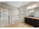 Well-lit bathroom features a large tub, glass shower, and double vanity sinks at 10322 E Topaz Ave, Mesa, AZ 85212