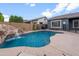 Gorgeous pool with rock waterfall feature, surrounded by a block wall and greenery at 10322 E Topaz Ave, Mesa, AZ 85212