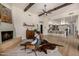 Spacious living room featuring wood beam accents, a cozy fireplace, stylish furniture, and an open-concept layout with kitchen view at 11343 E Appaloosa Pl, Scottsdale, AZ 85259