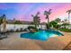 Backyard swimming pool with rock waterfall feature, lush landscaping, and a view of the twilight sky for a serene outdoor experience at 11343 E Appaloosa Pl, Scottsdale, AZ 85259