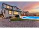 Exterior view of backyard and patio at dusk, featuring a pool and privacy fence at 12918 W Caraveo Pl, Peoria, AZ 85383