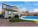 A backyard featuring a pool, artificial turf, and a two-story home with large windows at 12918 W Caraveo Pl, Peoria, AZ 85383