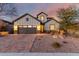 Beautiful home exterior featuring a well-manicured yard, brick driveway, and warm lighting at 12918 W Caraveo Pl, Peoria, AZ 85383