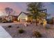 Exterior elevation showcasing a home with a two-car garage, desert landscaping, and dusk sky at 12918 W Caraveo Pl, Peoria, AZ 85383