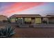 Back of home with a covered patio, fenced yard, and desert landscaping at sunset at 15116 W Carbine Way, Sun City West, AZ 85375