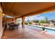 Covered patio with an outdoor dining area overlooks a sparkling pool and lush desert landscaping at 15646 E Sunflower Dr, Fountain Hills, AZ 85268