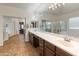 Bright bathroom featuring double vanity with a large mirror, sliding glass shower and tub at 17470 W Gelding Dr, Surprise, AZ 85388