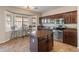 Kitchen featuring dark wood cabinetry, stainless steel appliances, granite countertops, island, and breakfast nook with bay window at 17470 W Gelding Dr, Surprise, AZ 85388