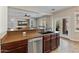 Close up view of a kitchen with stainless steel appliances, dark wood cabinets, a breakfast bar, and an open floor plan to the living room at 17470 W Gelding Dr, Surprise, AZ 85388