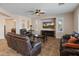 Cozy living room featuring comfortable leather seating, a ceiling fan, a fireplace, and a large television screen at 17470 W Gelding Dr, Surprise, AZ 85388