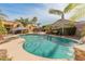 Backyard with a private pool, palm trees, lounge chairs, and lush landscaping at 17470 W Gelding Dr, Surprise, AZ 85388