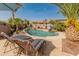 Inviting pool with a waterfall feature is surrounded by lush palm trees and comfortable lounge seating at 17470 W Gelding Dr, Surprise, AZ 85388