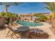 View of a backyard pool with a waterfall feature, tropical plants, and outdoor seating at 17470 W Gelding Dr, Surprise, AZ 85388