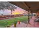 Backyard patio with a manicured lawn, sunset views, string lights and desert landscaping at 1844 E Cinnabar Ave, Phoenix, AZ 85020