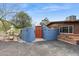 Private desert home entrance with a blue wall, wooden gate, and desert landscaping at 1844 E Cinnabar Ave, Phoenix, AZ 85020