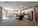 Spacious kitchen with granite countertops, a dark island, white cabinets, and stainless steel appliances flowing to living area at 19975 W Glenrosa Ave, Litchfield Park, AZ 85340