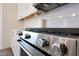 Close-up of stainless steel oven with knobs, white subway tile backsplash, and white cabinets at 19990 W Turney Ave, Litchfield Park, AZ 85340