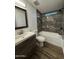 Updated bathroom featuring a wooden vanity and tub with marble tile surround and modern fixtures at 2034 E Charleston Ave, Phoenix, AZ 85022