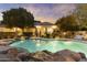 Gorgeous pool with stone accents and black wrought iron fence against a home with a covered patio at 2170 E Caroline Ln, Tempe, AZ 85284