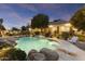 Backyard pool with rock features, diving board, and a covered patio, surrounded by lush landscaping at 2170 E Caroline Ln, Tempe, AZ 85284