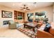 Spacious living room featuring a fireplace, built-in shelving, ceiling fan, and a leather sectional at 22813 N Del Monte Dr, Sun City West, AZ 85375