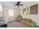 Comfortable bedroom features a ceiling fan, chair, unique green sofa, and colorful wall art at 2638 E Edgemont Ave, Phoenix, AZ 85008