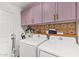 Modern laundry room with purple cabinets, decorative backsplash, washer, and dryer at 2638 E Edgemont Ave, Phoenix, AZ 85008