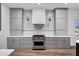 Modern kitchen features white backsplash, stainless steel stove, modern range hood, and gray cabinetry at 30600 N Pima Rd # 24, Scottsdale, AZ 85266