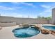 Inviting backyard spa with rock accents surrounded by a sand colored patio and a backdrop of desert landscaping at 30600 N Pima Rd # 24, Scottsdale, AZ 85266