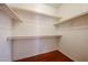 A walk-in closet features built-in shelving and a hanging rod for storage with wood floor at 34705 N 26Th Ave, Phoenix, AZ 85086